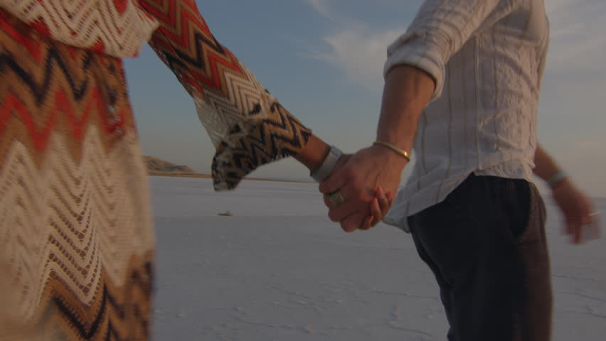 Interracial couple Walking and Holding at sunset in barren environment