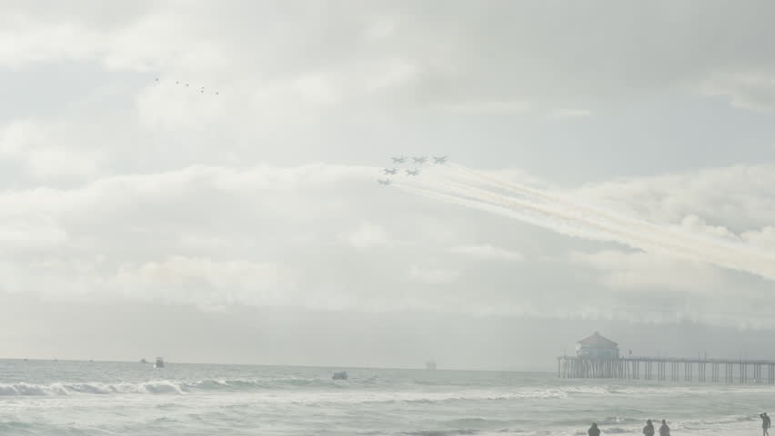 Panning Shot Of Fleet Of Airplane Flying Over Wavy Sea At Beach On Sunny Day - Huntington Beach, California