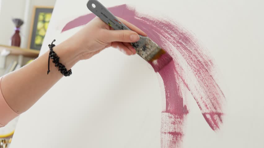 Brush drawing curved line with red acrylic paint. Drawing process. Young woman painter draws with paint brush and acrylic colors creating artwork. Unrecognizable painter drawing. Close-up in 4K, UHD