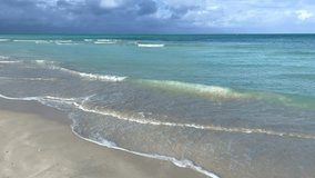 A beautiful Cuban beach in Varadero, Cuba, where you can see the waves and ocean waters on a cloudy day with the sun breaking through the clouds. Turquoise waves. 4K Video