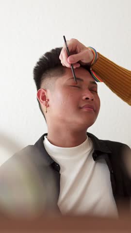 Gay couple applying make up with a shelf with cosmetics