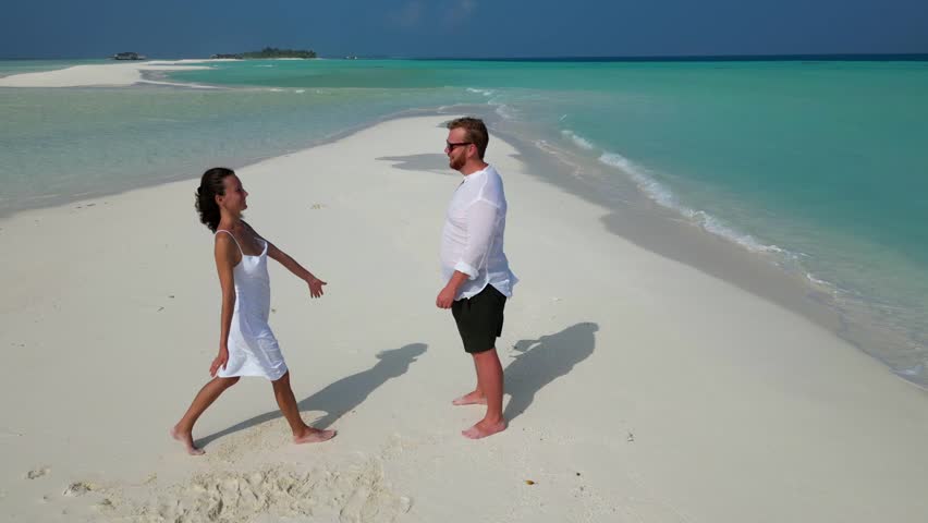Aerial view of happy couple in love in white clothes spending great time together on Maldives