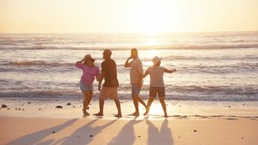 Camera tracks group of mature couples having fun on summer vacation walking along beach and splashing through waves on shoreline in South Africa - shot in slow motion - Powered by Shutterstock - Get 15% off with code: PIKWIZARD15