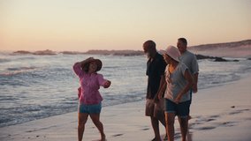 Group of mature couples having fun on summer vacation running and walking along beach and splashing each other in waves in South Africa - shot in slow motion - Powered by Shutterstock - Get 15% off with code: PIKWIZARD15