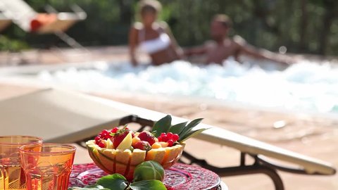 coffee table with fruit salad and man and woman in a jacuzzi