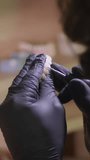 Vertical video. Dental technician in gloves polishes ceramic dentures in his workshop.