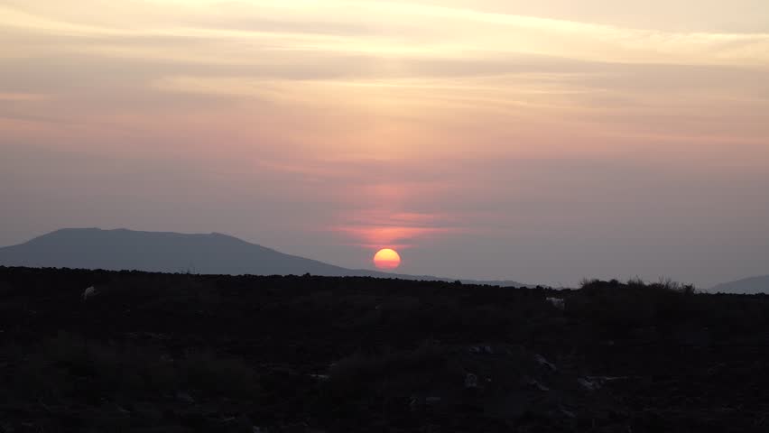silhouette of a man walking on a hill in the background of a sunset