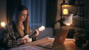 A Young Beautiful Blonde Woman Learns to Play the Ukulele by taking Online Lessons