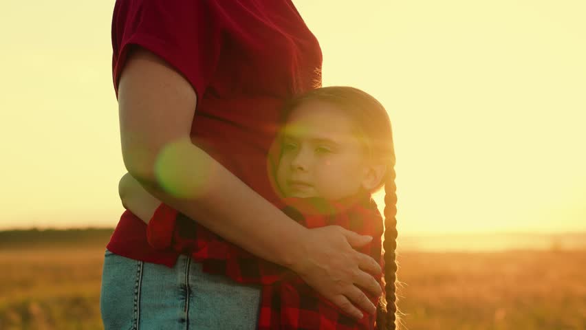 Cute little girl hugging mother with love and tenderness at summer field sunset sunrise closeup. Adorable female kid child embrace cuddle mom woman parent with best feelings outdoor meadow sun glare Royalty-Free Stock Footage #3466515713