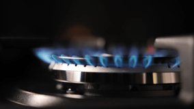 Blue gas fire on the kitchen stove close-up. Kitchen gas stove in the dark. Fire lights up in the burner of the gas stove. the energy crisis and rising energy prices. Slow motion video