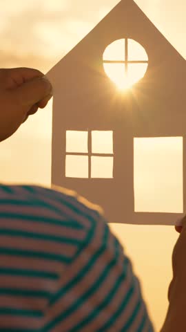 Home for children, parents. Building house for child Concept. Hands of child boy hold paper house at sunset, sun shines through window. Symbol of home for family, happiness. Dream of buying house. Sun Royalty-Free Stock Footage #3466529847
