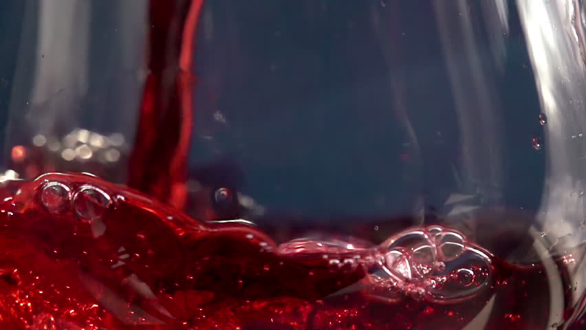 Pouring Red Wine. Slow Motion. Red Wine is poured into the glass on a blue background