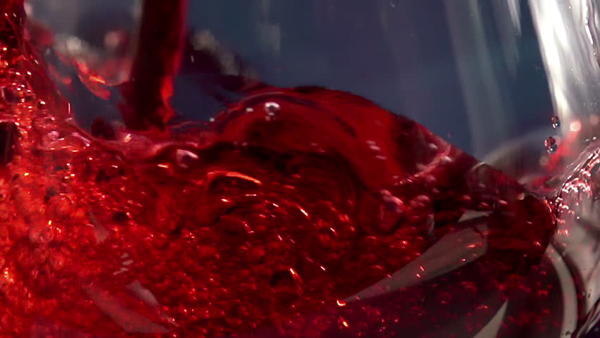 Pouring Red Wine. Slow Motion. Red Wine is poured into the glass on a blue background