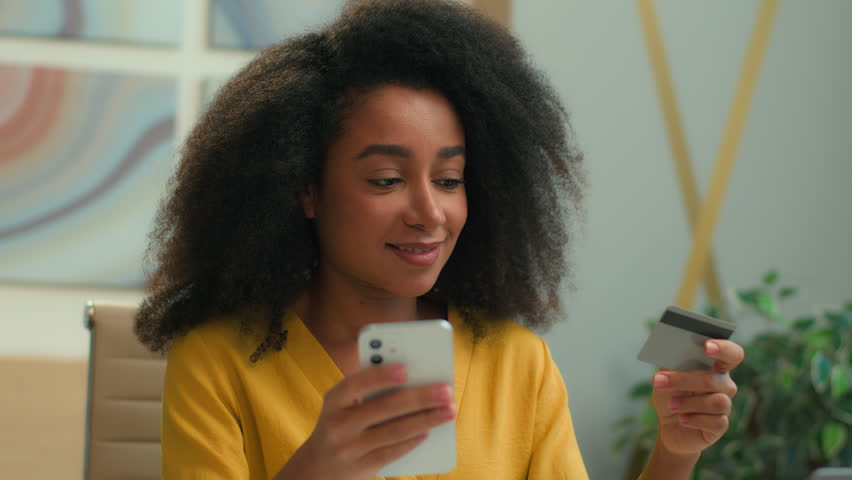 Happy cheerful African American business woman customer businesswoman joyful girl smiling easy shopping with credit card mobile phone smartphone payment order buying online bank money pay in office