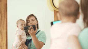 Modern Motherhood and Technology. Young Mother with Baby Engaged with Mobile Phone at Home