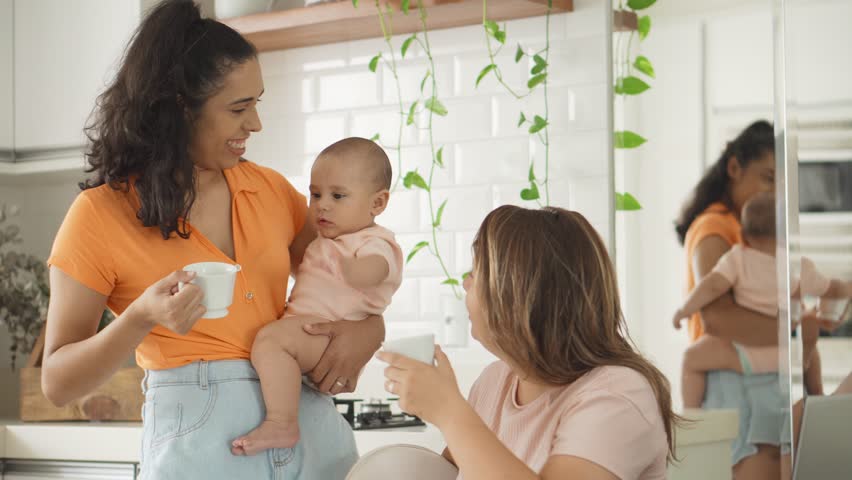 Joyful Lesbian Couple with Baby Enjoying Daily Life. Happy Mothers Playing with Infant at Home, Sharing Attention and Love.