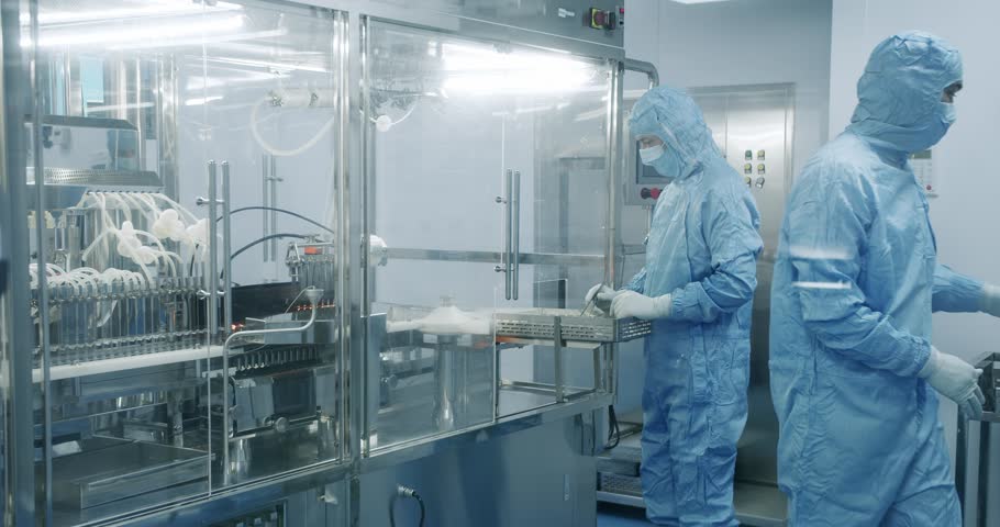 Factory Cleanroom. Pharmaceutical, Biotechnological and Semiconductor Creating Manufacturing Process. Scientists in Sterile Protective Clothing Work on a Modern Laboratory.