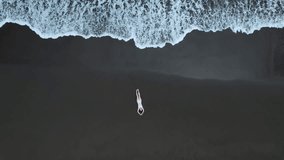 Beautiful drone video of girl sitting on a black beach from Tortuguero national park, Costa Rica