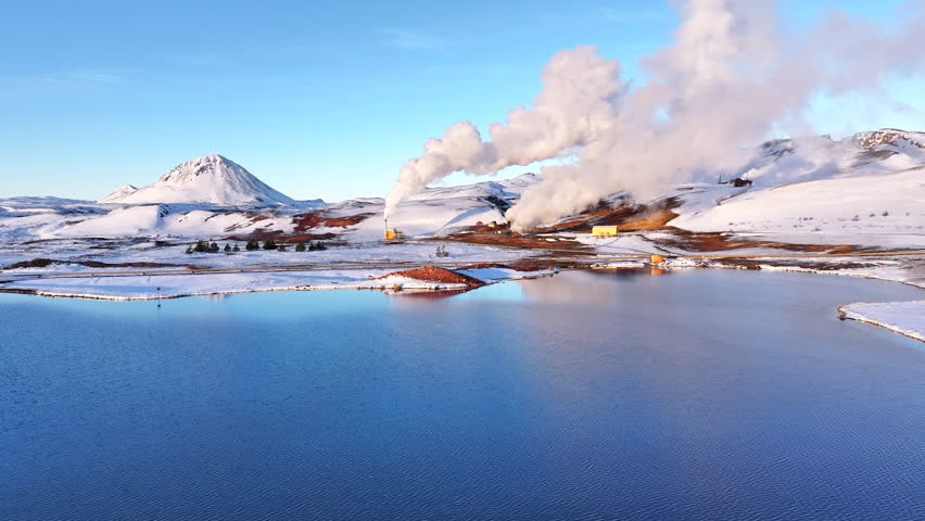 Winter view of Myvatn volcano and geothermal power plant in Iceland, steam rising against blue skies