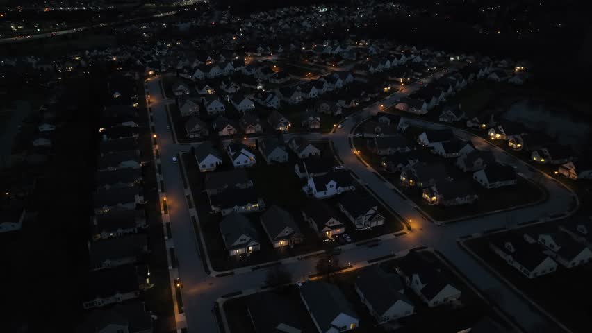 High aerial shot of dark neighborhood at night. Development with house and street lights in USA housing area.