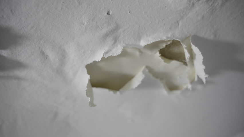 Peeling dry paint falling off wall or ceiling in bathroom or shower room in house or apartment. Close up - cracks of white paint falling apart in neglected place with moisture or humidity condensation
