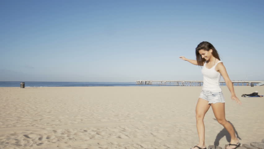 happy young balance on wood bollards at the beach in california.