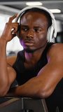 African american man in sportswear listens to music while training at gym. Vertical video