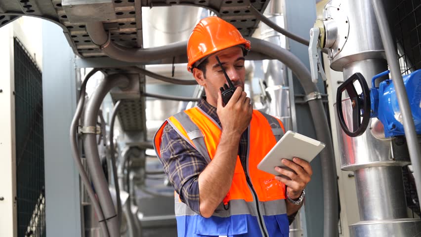 Foreman engineer  wearing reflective jacket, engineering helmet, standing inspecting plumbing system, safety and maintenance inspection on rooftop of construction building.