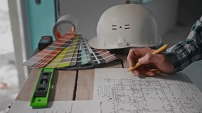 A man sitting at a table, drawing a blueprint with a pencil - Powered by Shutterstock - Get 15% off with code: PIKWIZARD15