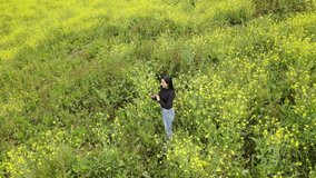 Floral contrasts between the serenity of yellow flowers and the modernity of a girl with a black t-shirt and her cell phone talking, outdoors, technology, healthy living, lifestyle,