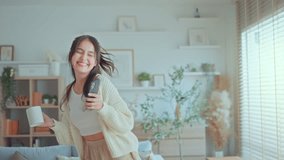 Happy carefree asian woman holding coffee cup and mobile smartphone have fun moving listening to music relax in living room, She dance enjoy leisure weekend at home. - Powered by Shutterstock - Get 15% off with code: PIKWIZARD15