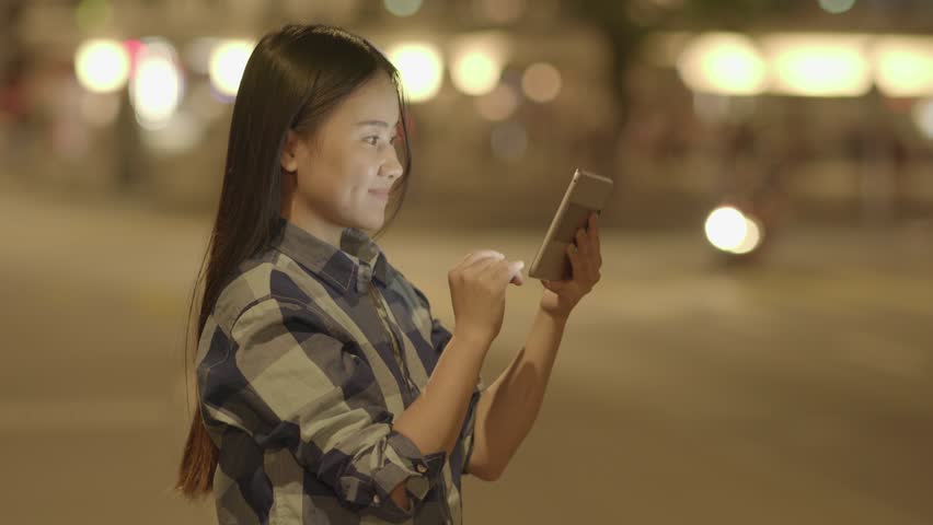 Smiling Woman as she Uses her Tablet in Urban Area