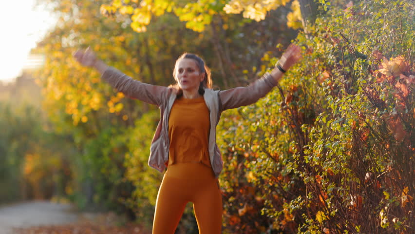 Hello autumn. fit woman in fitness clothes in the park doing HIIT workout.