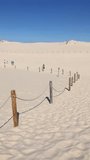 Leba Desert in Poland with people walking on a beach in sand as vertical video for social media
