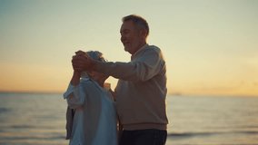Portrait happy senior family wife husband looking camera smiling dancing on sea beach at sunset. Old man hugging dancing with woman. Love romantic pensioner relationships, lifelong marriage concept. - Powered by Shutterstock - Get 15% off with code: PIKWIZARD15