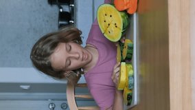 Vertical video. Cute child eating ripe yellow watermelon while sitting at table and surrounded by fresh organic exotical fruits, slow motion