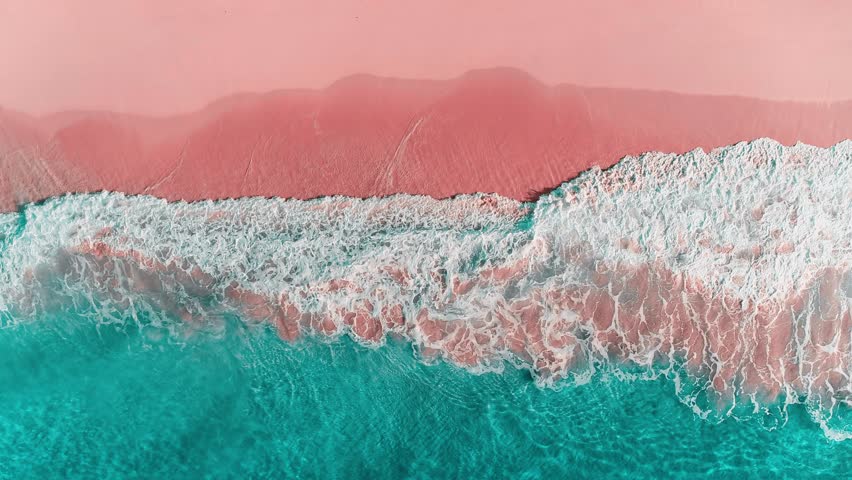Calm view of a transparent wave on a tropical paradise beach of the Caribbean Sea. Turquoise waves on pink sand. Green sea waters. Waves crash on the sandy beach. Changeable windy weather.