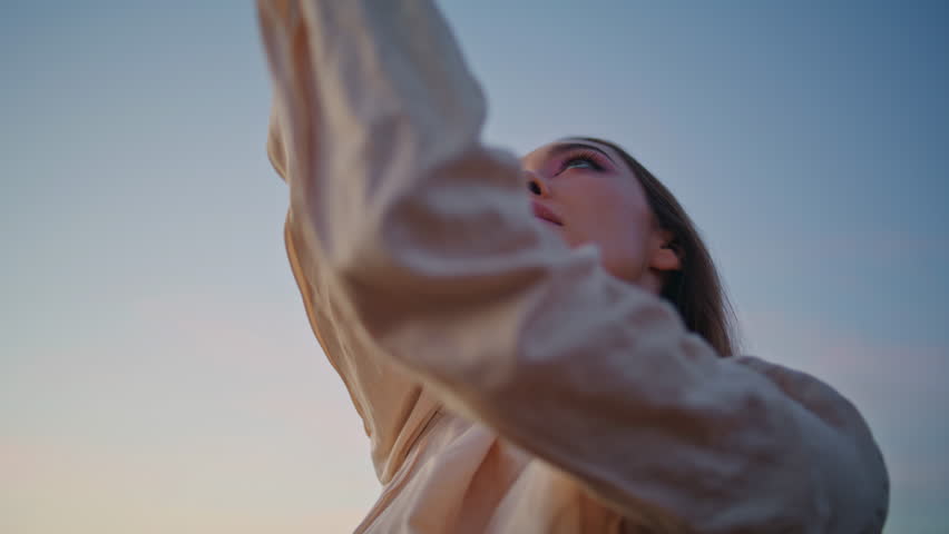 Closeup girl dancing arms sensually in front sunset sky. Portrait inspired seductive woman moving hands smoothly standing at abandoned nature. Attractive lady dancer looking camera posing outdoors 