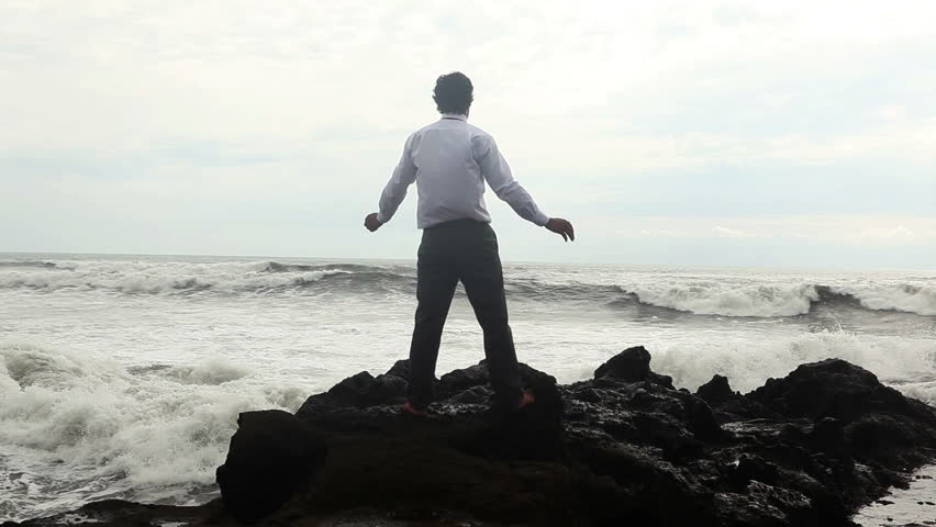 Businessman looking at ocean and showing freedom while sea storm