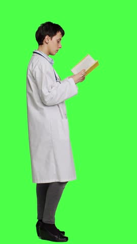 Profile Medic specialist reading a healthcare literature book to develop her medical expertise in the industry, stands against greenscreen backdrop. Clever doctor in white coat enjoys lecture. Camera Royalty-Free Stock Footage #3467207911