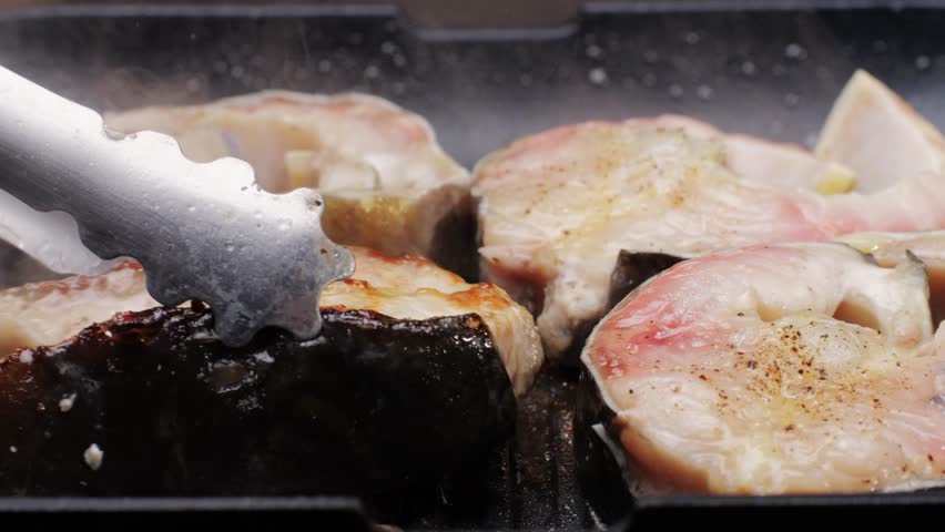 Cooking fillet sturgeon beluga white fat fish on grill or frying pan with oil close-up. Roast healthy food concept. Fry sturgeon, hake, cod fish steak pieces fillet. Healthy diet food with Omega 3. 