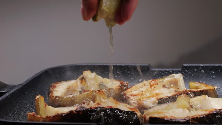 Cooking fillet sturgeon beluga white fat fish on grill or frying pan with oil close-up. Roast healthy food concept. Fry sturgeon, hake, cod fish steak pieces fillet. Healthy diet food with Omega 3. 