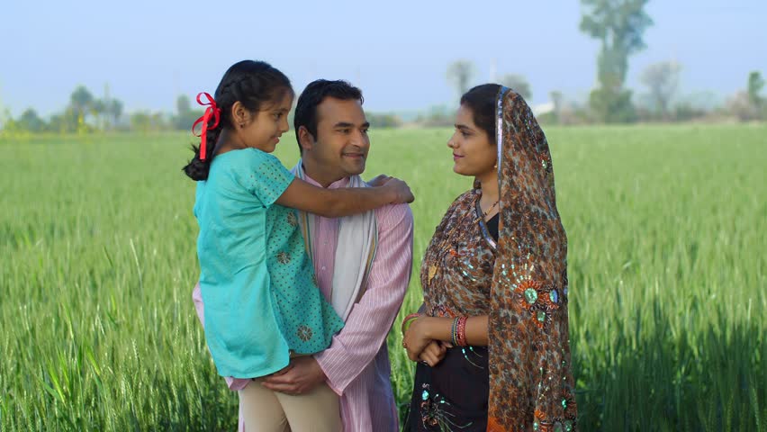 Happy Indian farmer family in fields - rural area, desi lifestyle, village life, nuclear family, girl child. Medium shot of a happy Indian family holding their daughter their arms - field, khet, be... Royalty-Free Stock Footage #3467292215