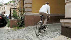 Slow motion steadicam footage of young man riding vintage bicycle in passage way with paved road