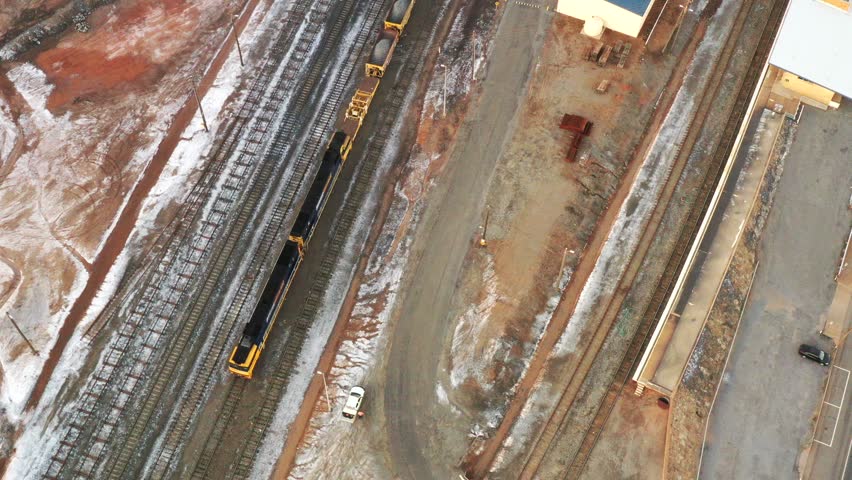 Broken Hill train station railways up to sunrise sky with mine hills – aerial 4k view.
