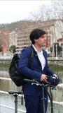 vertical portrait 4K video, the businessman in a sharp blue suit is seen carefully putting on his helmet before embarking on his bicycle commute, ensuring a safe journey