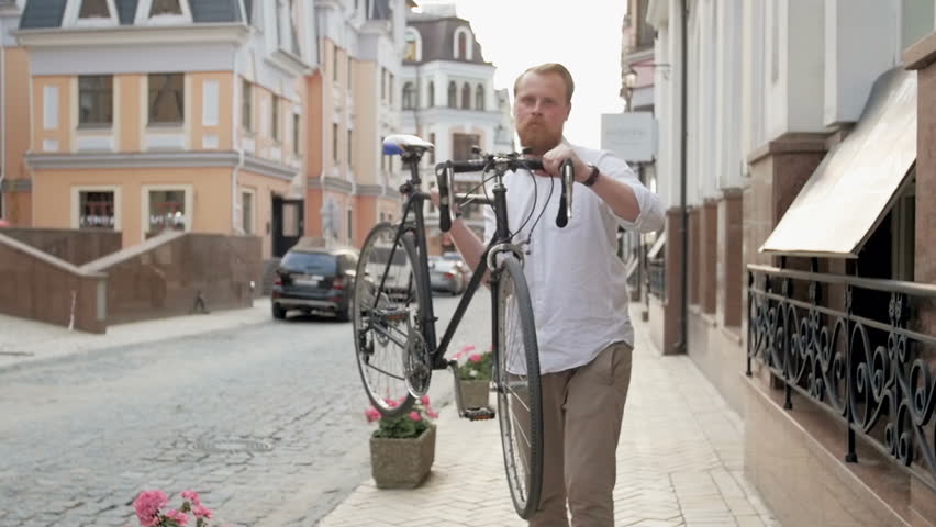 Slow motion video of stylish young man carrying old vintage bicycle on shoulder
