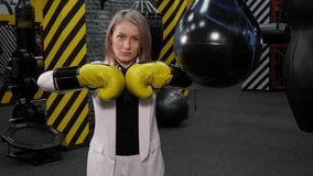 Close-up of a strong successful business woman in boxing gloves in the gym against the background of a boxing ring. - Powered by Shutterstock - Get 15% off with code: PIKWIZARD15