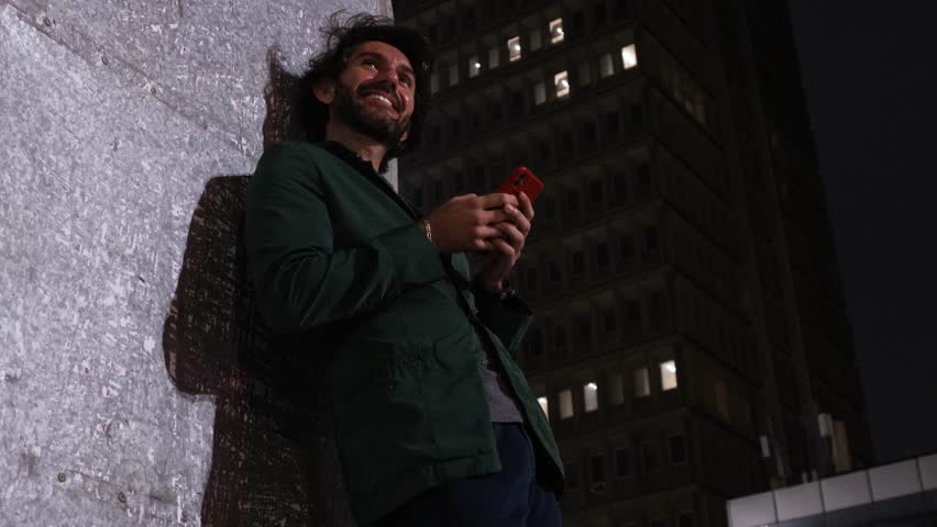 View of one young man with smartphone at night time with city view landscape and traffic lights in the background mobile phone