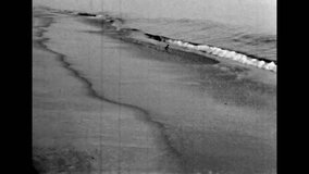 Black white film, sea waves tide on sand beach, close up. Archival seascape video. Old ocean shore nature. Vintage scenic shore landscape. Archival sandy coast. Seaside nostalgia. Retro archive 1980s